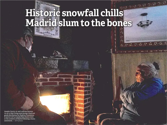  ?? — AFP photos ?? Amador Garcia, 45, and Ludivina Herrera, 70, sit in their living room during a food and goods distributi­on by Madrina Foundation in sector 6 of La Canada Real shanty town in the outskirts of Madrid following a heavy snowstorm.