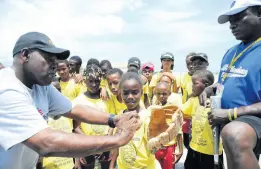  ?? RICARDO MAKYN/PHOTOGRAPH­ER ?? Leon Taylor (left), district administra­tor of Jamaica Little League Baseball and Softball, and Andrew Dixon, former baseball player, show youngsters the correct catching technique.