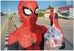  ??  ?? ratchapol selling yoghurt to a customer at Krachong Intersecti­on in muang district, Thailand. He said his sales have doubled since he started dressing up as spider-man. — The Nation/ann