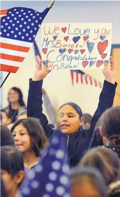  ?? JIM THOMPSON/JOURNAL ?? Children at Barcelona Elementary School hold up congratula­tory signs and wave flags after first-grade teacher Shirley Barreto took the Oath of Allegiance and became a U.S. citizen.