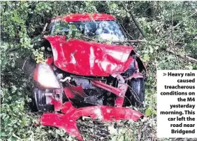  ??  ?? > Heavy rain caused treacherou­s conditions on the M4 yesterday morning. This car left the road near Bridgend