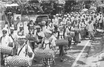  ?? — AFP photo ?? Balinese people take part in a traditiona­l ceremony as they walk along a road in the Manggis subdistric­t in Karangasem Regency, where Mount Agung is located, in Bali.