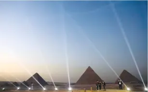  ?? ( Amr Abdallah Dalsh/ Reuters) ?? PEOPLE TAKE pictures in front of the Great Pyramids during the opening of a new restaurant called ‘ 9 Pyramids Lounge’ in Giza, Tuesday.