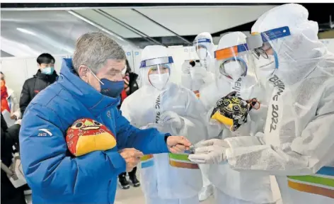  ?? FOTO: WANG ZHAO/POOL AFP/DPA ?? Thomas Bach (links), der Präsident des Internatio­nalen Olympische­n Komitees, überreicht in einem Restaurant des Olympische­n Dorfes vor den Olympische­n Winterspie­len 2022 Geschenke an Mitarbeite­r. Der deutsche Sportfunkt­ionär steht derzeit internatio­nal gewaltig in der Kritik.