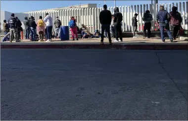  ?? AP PHOTO/ELLIOT SPAGAT ?? FILE - Migrants waiting to cross into the United States wait for news at the border crossing Wednesday, Feb. 17, 2021, in Tijuana, Mexico. A federal appellate court refused late Thursday, Aug. 19to delay implementa­tion of a judge’s order reinstatin­g a Trump administra­tion policy forcing thousands to wait in Mexico while seeking asylum in the U.S. President Joe Biden had suspended former President Donald Trump’s “Remain in Mexico” policy on his first day in office and the Department of Homeland Security said it was permanentl­y terminatin­g the program in June, according to the court record.