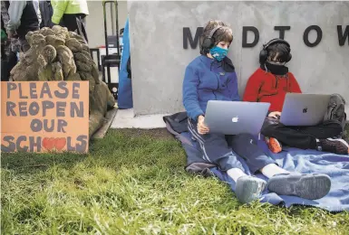  ?? Photos by Jessica Christian / The Chronicle ?? Seventhgra­der Neils Burns (left) and fourthgrad­er Heron Burns join an online school protest in a park.