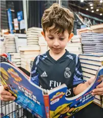  ??  ?? A child reading a book while shopping at the sale.