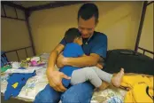  ?? JULIO CORTEZ — THE ASSOCIATED PRESS ?? Elmer Maldonado, a migrant from Honduras, hugs his 1-year-old son at a shelter in Harlingen, Texas, on Monday.