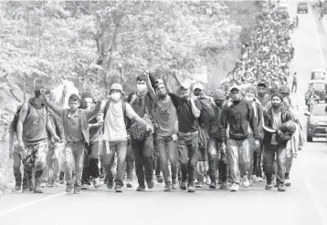  ?? JOSUE DECAVELE/GETTY ?? Heading north: Migrants walk after breaking through a police barricade at a border checkpoint Saturday in El Florido, Guatemala. The caravan left Honduras to walk across Guatemala and Mexico to the United States. Central Americans expect to receive asylum and most Hondurans opted to migrate after two hurricanes hit the region in 2020.