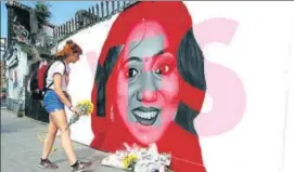  ?? AP ?? A woman places flowers by a mural showing Savita Halappanav­ar, a 31yearold Indian dentist who had sought and been denied an abortion before she died after a miscarriag­e in a Galway hospital.
