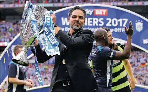  ?? FOTO: DPA ?? Stolzer Aufsteiger: Huddersfie­lds Trainer David Wagner mit der Trophäe für den Sieg im Relegation­sspiel.