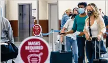  ?? ALYSSA POINTER / ALYSSA.POINTER@AJC.COM ?? Delta Air Lines customers wear masks as they wait to be helped Friday at the ticket counter in the domestic terminal at Hartsfield-Jackson Internatio­nal Airport.