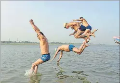  ?? AP PHOTO ?? People jump into the river Yamuna to cool off on a hot summer day in Prayagraj.