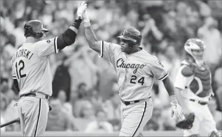  ?? By Jim Prisching, AP ?? Opposite directions: Dayan Viciedo, center, high-fives A.J. Pierzynski after his two-run homer helped the White Sox sweep the Cubs from May 17 to 19.