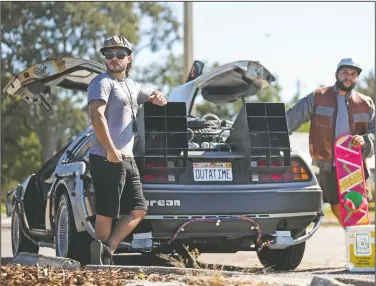  ?? (Tampa Bay Times/Dirk Shadd) ?? Bradley Despaigne (left) and Joseph Benson, 30, show off Despaigne’s 1981 DeLorean which they have made into a time machine replica DeLorean modeled off of the original “Back To The Future” movie, at Edgewater Drive Park in Clearwater, Fla. Despaigne purchased the DeLorean in September 2019 and the two have been working on it for a little over a year. “The way I see it, if you’re gonna build a time machine into a car, why not do it with some style,” said Despaigne, quoting Doc Brown.