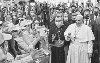  ?? Vincenzo Pinto / AFP via Getty Images ?? Children greet Pope Francis as he arrives Saturday at Baghdad’s Saint Joseph Cathedral on the second day of the first papal visit to Iraq. The pope made a plea for peace at an interrelig­ious service in southern Iraq.