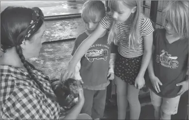  ?? File photo ?? From a few years ago, Tanya Ellis, holds a chicken for siblings Nero Jensen (left), Beatrix Jensen (middle), and Netta Jensen (right) to pet at Neubauer Farms.