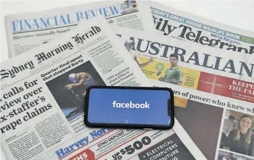  ?? LUKAS COCH / EFE ?? Un móvil con el logo de Facebook destaca ante la cabecera de varios periódicos australian­os.