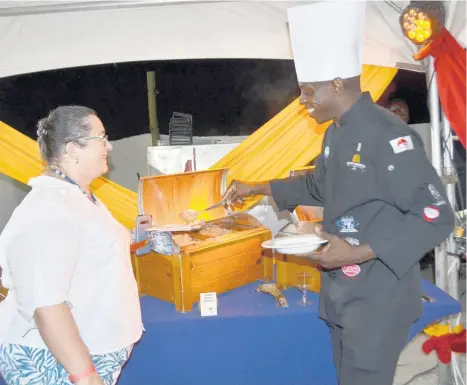  ??  ?? Hedonism II’s Executive Chef Michael Barnett serves some tasty Indian butter chicken to Negril Chamber of Commerce Director Sophie Grizzle.