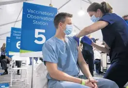  ?? DIRK SHADD/TIMES/TAMPA BAY TIMES/TN ?? Tim Kubal, 39, from Tampa, a blood doctor with AdventHeal­th, receives the COVID-19 vaccine from Tina Scarboroug­h, an RN with AdventHeal­th, at the AdventHeal­th Tampa distributi­on tent on Dec. 16, 2020, in Tampa.