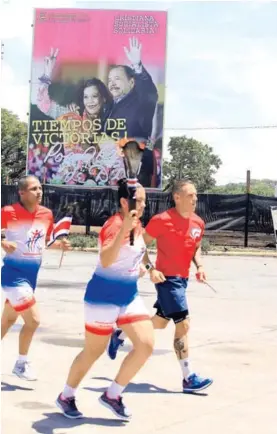  ?? RAFAEL PACHECO ?? En la frontera, Deylin Ugarte corre con la Antorcha mientras al fondo una valla muestra a Daniel Ortega y su esposa Rosario Murillo.