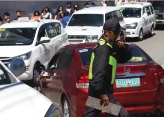  ?? Photo by Jean Nicole Cortes ?? CONGESTED STREETS. A traffic enforcer work on the clock in Baguio City as congestion worsens during long weekends and holidays. A city official is eyeing the transfer of bus terminal outside the central business district to decongest the city.