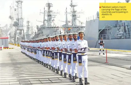  ?? AFP ?? ■ Pakistani sailors march carrying the flags of the countries participat­ing in AMAN-19.