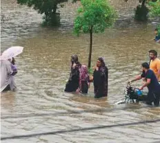  ?? AFP ?? People wade through a flooded street in the city.