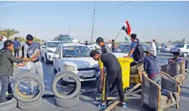  ?? (AFP) ?? Iraqi protesters use tyres to block the road to Najaf airport during a demonstrat­ion, in Najaf on Wednesday