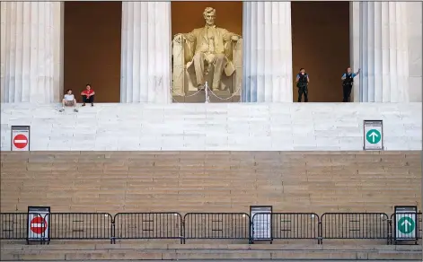  ?? (File Photo/AP/Patrick Semansky) ?? Visitors (left) sit as members of the U.S. Park Police (right) stand June 7 at the Lincoln Memorial in Washington.