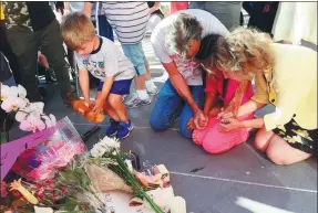  ?? REBECCA BOONE / ASSOCIATED PRESS ?? A boy places a stuffed animal as other people kneel at a memorial during a vigil at City Hall in Boise,