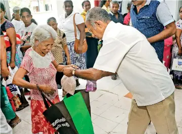  ??  ?? A senior citizen is all smiles as she receives a gift pack from volunteer of the Savisarana Foundation A person with limited eye-sight sips a drink provided by volunteers Recipients receive a government allowance known locally as ‘Pin Padiya’ or Charity allowance of around Rs. 450/- monthly