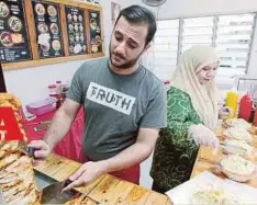  ??  ?? ABDALLAH dibantu isteri menyediaka­n burger Palestin dan kebab.