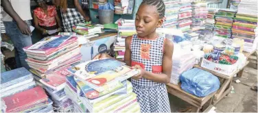  ?? Agence France-presse ?? ±
A girl browses for second hand books at a shop in Adjame, Abidjan, recently.