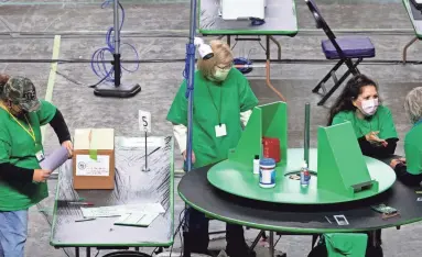  ?? MARK HENLE/THE REPUBLIC ?? Contractor­s hired by the Arizona Senate examine and recount Maricopa County ballots from the 2020 general election on Wednesday at Veterans Memorial Coliseum in Phoenix.