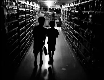  ?? Kent Porter/The Press Democrat via
AP ?? In this 2019 file photo, Elijah Carter 11, (left) and Robert Haralson, 12, help shop for their parents in a darkened Olivers Supermarke­t during a blackout in the Rincon Valley community in Santa Rosa, Calif.