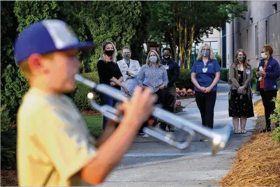  ?? CURTIS COMPTON / CCOMPTON@AJC.COM ?? Renfroe Middle School sixth-grader Jason Zgonc plays his trumpet Wednesday outside Emory Decatur Hospital to entertain, thank and inspire front-line workers. He has become the talk of the facility, showing up around 8 p.m. for weeks.