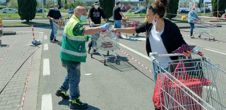  ?? (foto Cambi/Sestini) ?? Un volontario del servizio anticendio distribuis­ce bottigliet­te d’acqua a chi è in coda davanti alla Coop di Ponte a Greve