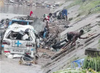  ?? FATI BRAIMAH/AFP/GETTY IMAGES ?? People try to remove valuables submerged in a flood after at least more than 150 people were killed in a gas station explosion and fire in Ghana’s capital, Accra, on Thursday.