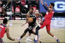  ?? KATHY WILLENS — THE ASSOCIATED PRESS ?? Nets guard Kyrie Irving, center, drives between Washington guard Garrison Mathews (24) and forward Troy Brown Jr., (6) during a preseason game Sunday.