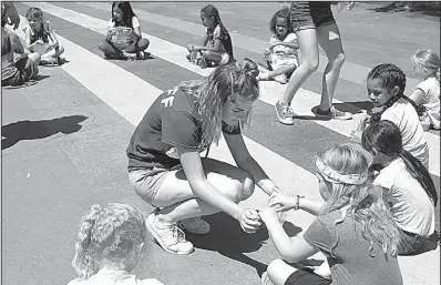 ?? Los Angeles Times/RICK LOOMIS ?? Michaela Capps, 17, helps a group of Girl Scouts with an experiment during a summer day camp in Long Beach, Calif., earlier this month.