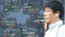  ??  ?? A man walks past an electronic stock board showing world market numbers at a securities firm in Tokyo. Asian stocks meandered Wednesday as investors awaited Fed Chair Janet Yellen’s speech Friday for clues on interest rates. Eugene Hoshiko, The...