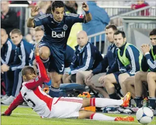  ?? CHRIS YOUNG/ THE CANADIAN PRESS ?? Camilo Sanvezzo of the Vancouver Whitecaps jumps over the challenge from Toronto FC’S defender Jeremy Hall during first- half action Wednesday in the second leg of the Amway Canadian Championsh­ip final in Toronto. TFC won the game and title.