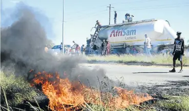  ?? Picture: Tiro Ramatlhats­e ?? Not even the sidewalk brush or a cement truck was safe in Mahikeng this week. Grass was set alight while looters tried to steal what they could from the truck during riots in the North West town.