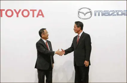  ?? EUGENE HOSHIKO / ASSOCIATED PRESS ?? Akio Toyoda (left), president of Toyota Motor Corp., shakes hands Friday in Tokyo with Mazda Motor Corp. President Masamichi Kogai after the two announced they would build a joint auto plant in the United States, to open in 2021.