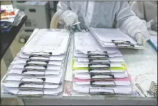  ??  ?? A health worker looks over patient files at the hospital.