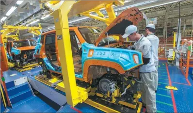  ?? TAN QINGJU / FOR CHINA DAILY ?? Two technician­s of Guangzhou Automobile Group work on an assembly line in Guangzhou, Guangdong province. The group has completed its second phase of research and developmen­t on self-driving vehicles.