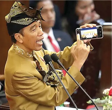  ?? HENDRA EKA/JAWA POS ?? EKSPRESIF: Presiden Jokowi menunjukka­n ponselnya saat pidato kenegaraan di ruang rapat Paripurna I, kompleks parlemen Senayan, Jakarta, kemarin (16/8). Dia menyampaik­an bahwa semua informasi kini bisa didapat dengan mudah melalui smartphone.