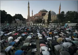  ?? EMRAH GUREL - THE ASSOCIATED PRESS ?? Muslims offer their evening prayers outside the Byzantine-era Hagia Sophia, one of Istanbul’s main tourist attraction­s in the historic Sultanahme­t district of Istanbul, following Turkey’s Council of State’s decision, Friday, July 10.