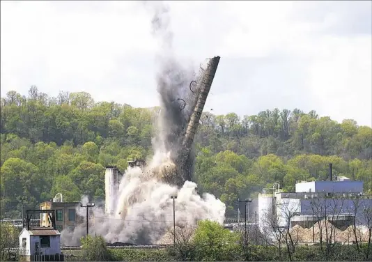  ??  ?? Dust and debris shoot skyward as a smokestack collapses Tuesday after it was imploded at the Shenango Coke Works on Neville Island.